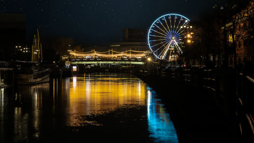 Illuminated bridge over river at night