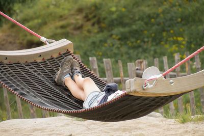 Low section of man relaxing on hammock at playground