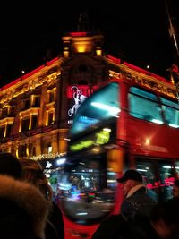 People on illuminated street against buildings at night