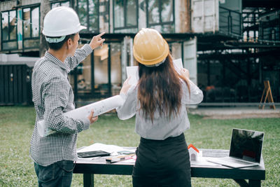 Rear view of a man with woman standing against built structure