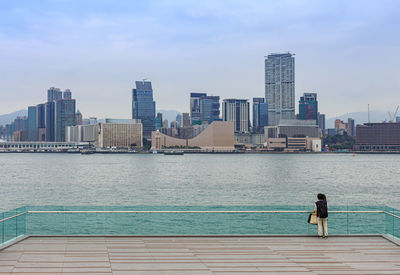 Rear view of man in swimming pool against buildings in city