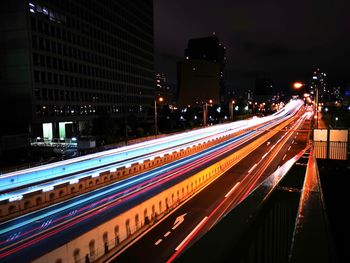 Light trails on road by buildings in city at night