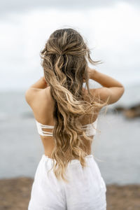 Rear view of young woman standing against sky