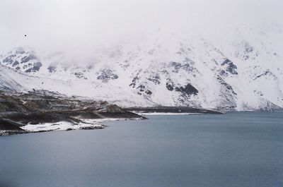 Scenic view of snowcapped mountains by sea against sky