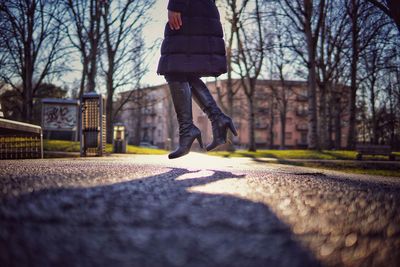 Low section of man walking by bare trees