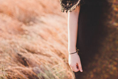 Cropped image of woman hand on field