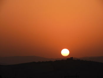 Silhouette landscape against orange sky