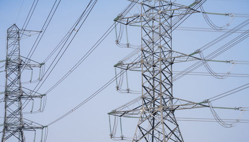 Low angle view of electricity pylon against clear sky