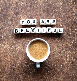 Directly above shot of coffee in cup with text on table