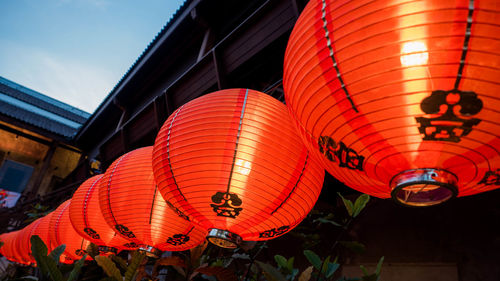 Low angle view of illuminated lanterns hanging by building