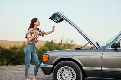 Rear view of woman using mobile phone while standing against white background