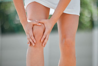 Low section of woman suffering from knee pain