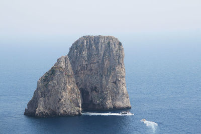 Large rock in sea against sky