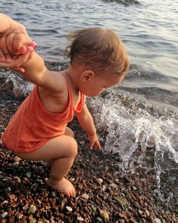 Cropped image of hand holding baby girl while playing at beach
