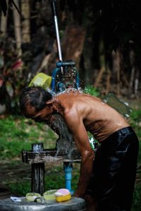 Rear view of shirtless man working in water