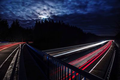 Light trails on highway against sky at night