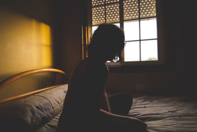 Side view of woman relaxing on bed at home