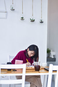 Woman writing on book at table