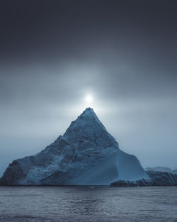Scenic view of snowcapped mountains by sea against sky