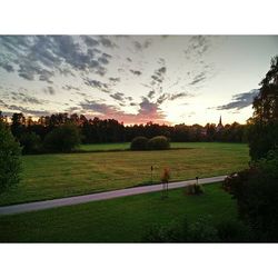 Scenic view of grassy field against sky at sunset