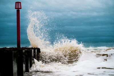 Waves splashing on shore against sky