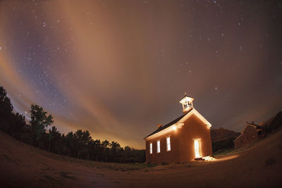 Building on field against sky at night