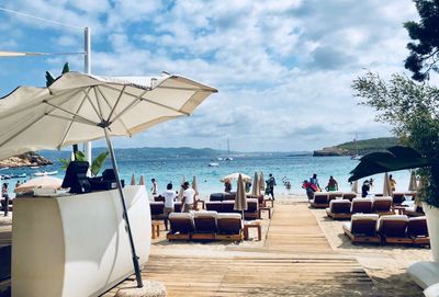 People sitting on chair by sea against sky