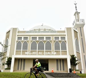 Man riding bicycle on building against sky