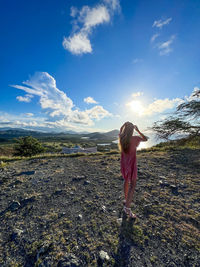 Rear view of woman standing on field against sky on the margarita island in venezuela 