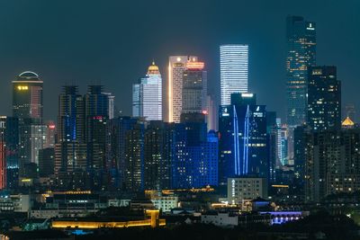 Illuminated buildings in city against sky at night
