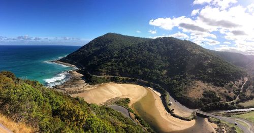 Scenic view of sea by mountains against sky