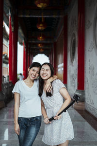 Portrait of smiling friends standing in corridor of temple