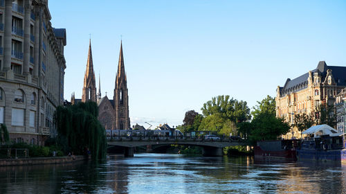 Bridge over river by buildings against sky in city