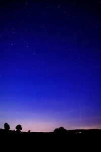 Low angle view of silhouette landscape against blue sky