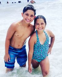 Portrait of siblings standing in water at beach
