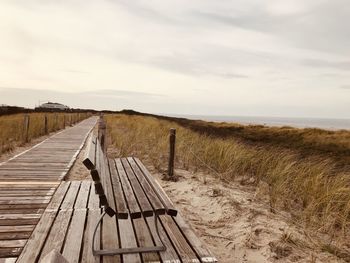 Wooden boardwalk on field against sky