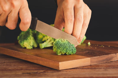 Midsection of person holding leaf on cutting board