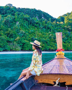 Man sitting on boat against trees