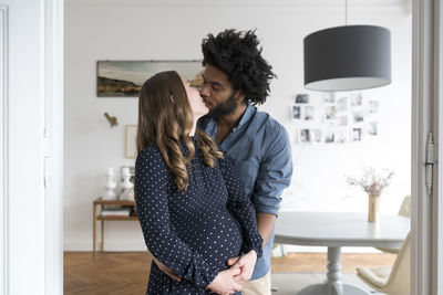 Kissing pregnant couple in living room