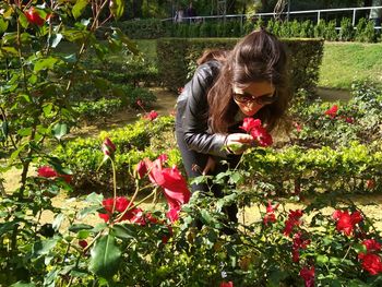 Young woman holding flower against plants