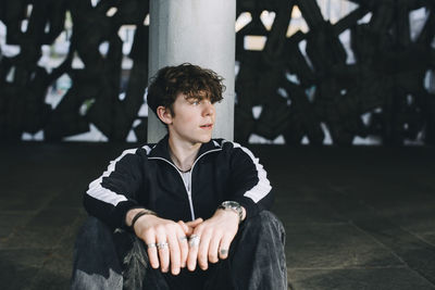 Teenage boy contemplating while sitting in parking garage