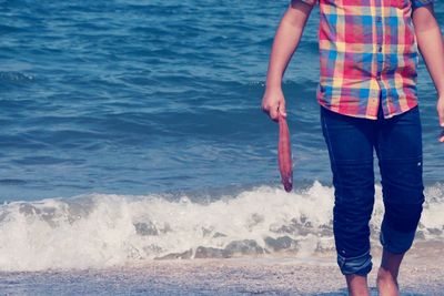 Low section of man standing in sea