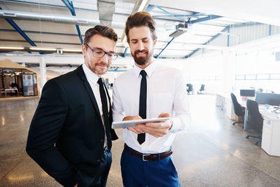 Smiling businessmen using digital tablet in office