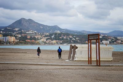 Rear view of people on beach against sky