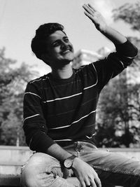 Young man sitting against sky