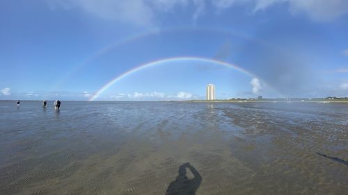 Scenic view of beach against rainbow in sky
