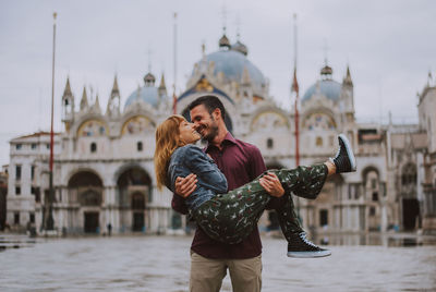 Smiling couple embracing against historic building