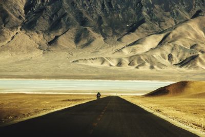 Scenic view of road amidst landscape with man riding motorcycle