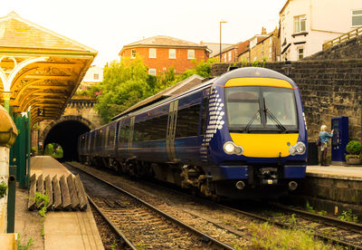 Train at railroad station in city against sky