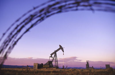 Mid distance view of derrick against sky during sunset